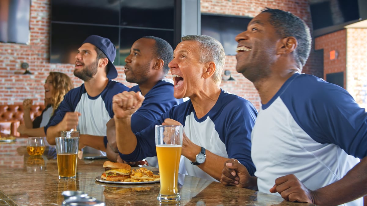 Multi-cultural friends watching football in sports bar eating food