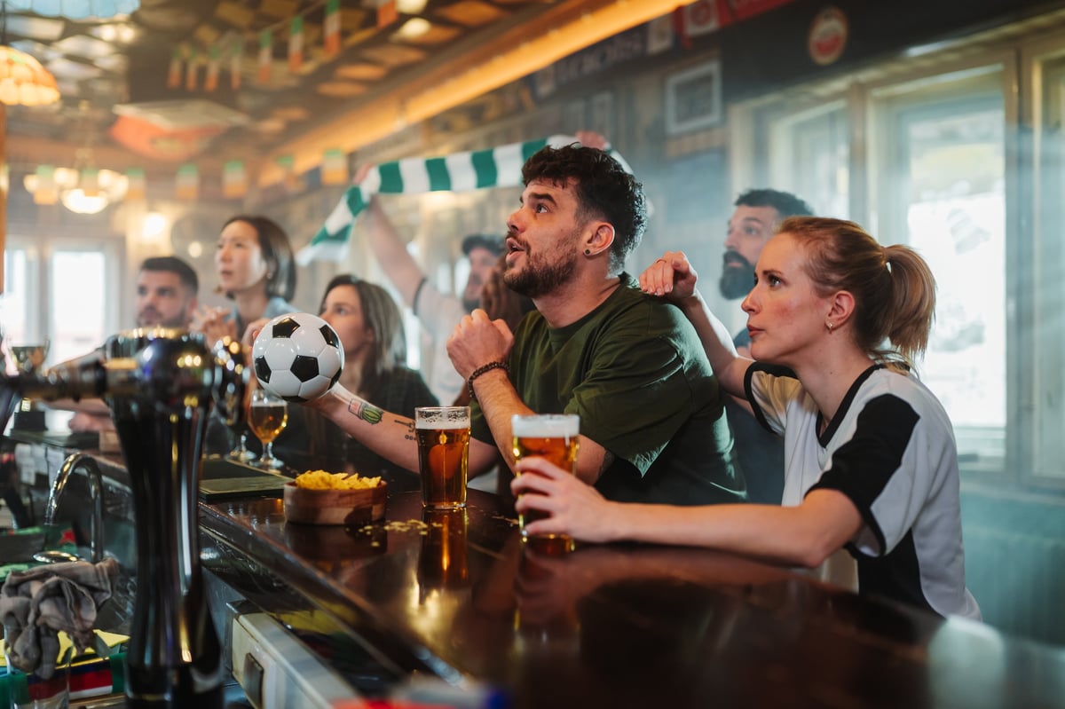 Football fans cheering in a pub watching a match on TV